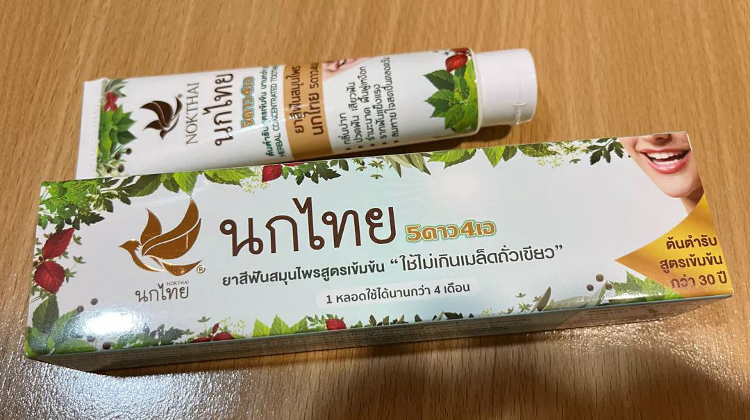 Nokthai Herbal Toothpaste tube placed on wooden background showing Thai herbal packaging