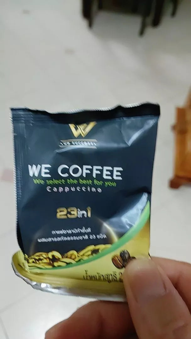 Hand holding a single sachet of WE Coffee 23 in 1 instant cappuccino herbal mix sugar free.