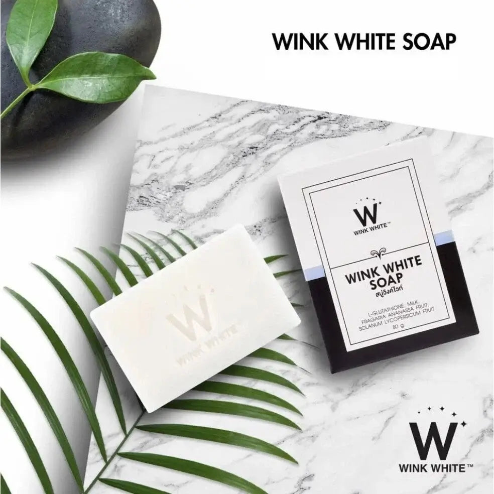 WINK WHITE SOAP on marble surface with green leaves, featuring L-Glutathione and goat milk for face and body cleansing.