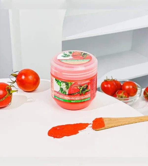 Carebeau Tomato Salt Scrub featuring a vibrant pink jar, fresh tomatoes, and scrub spilled on a white surface for skin exfoliation.