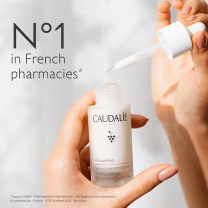 Hand holding Caudalie Vinoperfect Serum with No1 brightening serum claim
