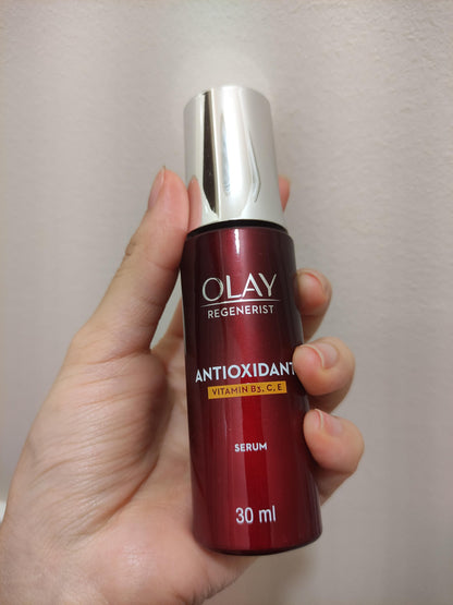 Hand holding Olay Regenerist Antioxidant Serum showing red bottle and silver pump