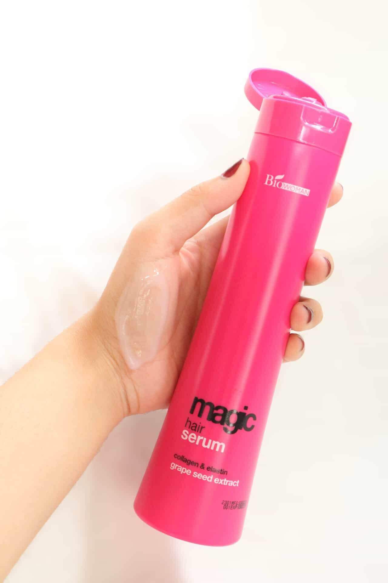 Close-up photo showing a hand holding the pink Biowoman Magic Hair Serum bottle, demonstrating the product size.