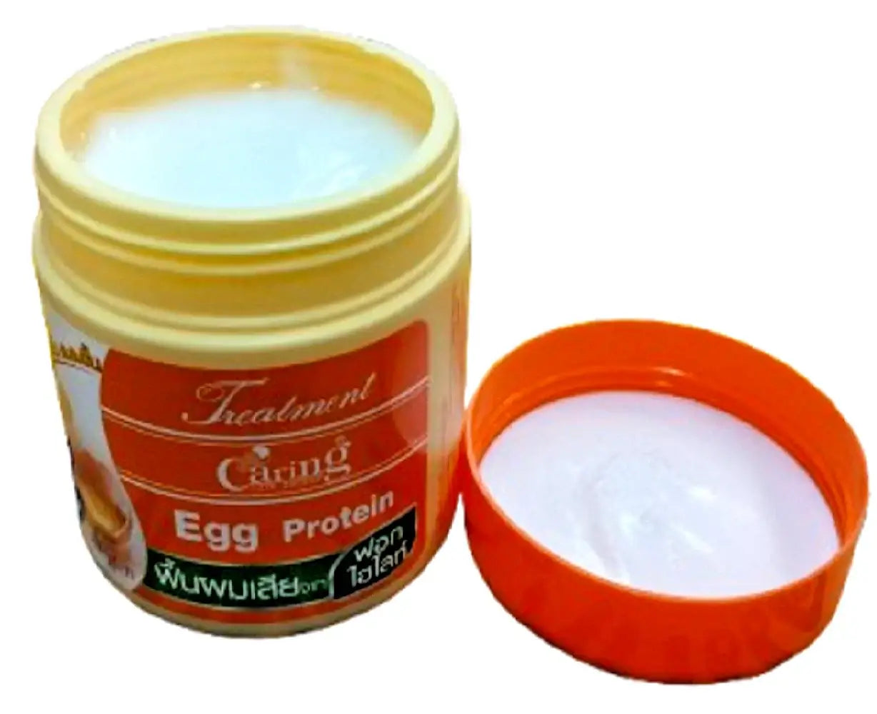 Open jar of Caring Egg Protein Treatment showing the rich cream texture inside next to its orange lid