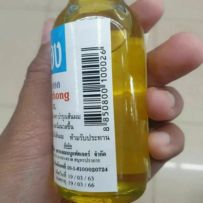 Chumpathong Olive Oil bottle held in hand, perfect for nourishing hair and skin spa care.