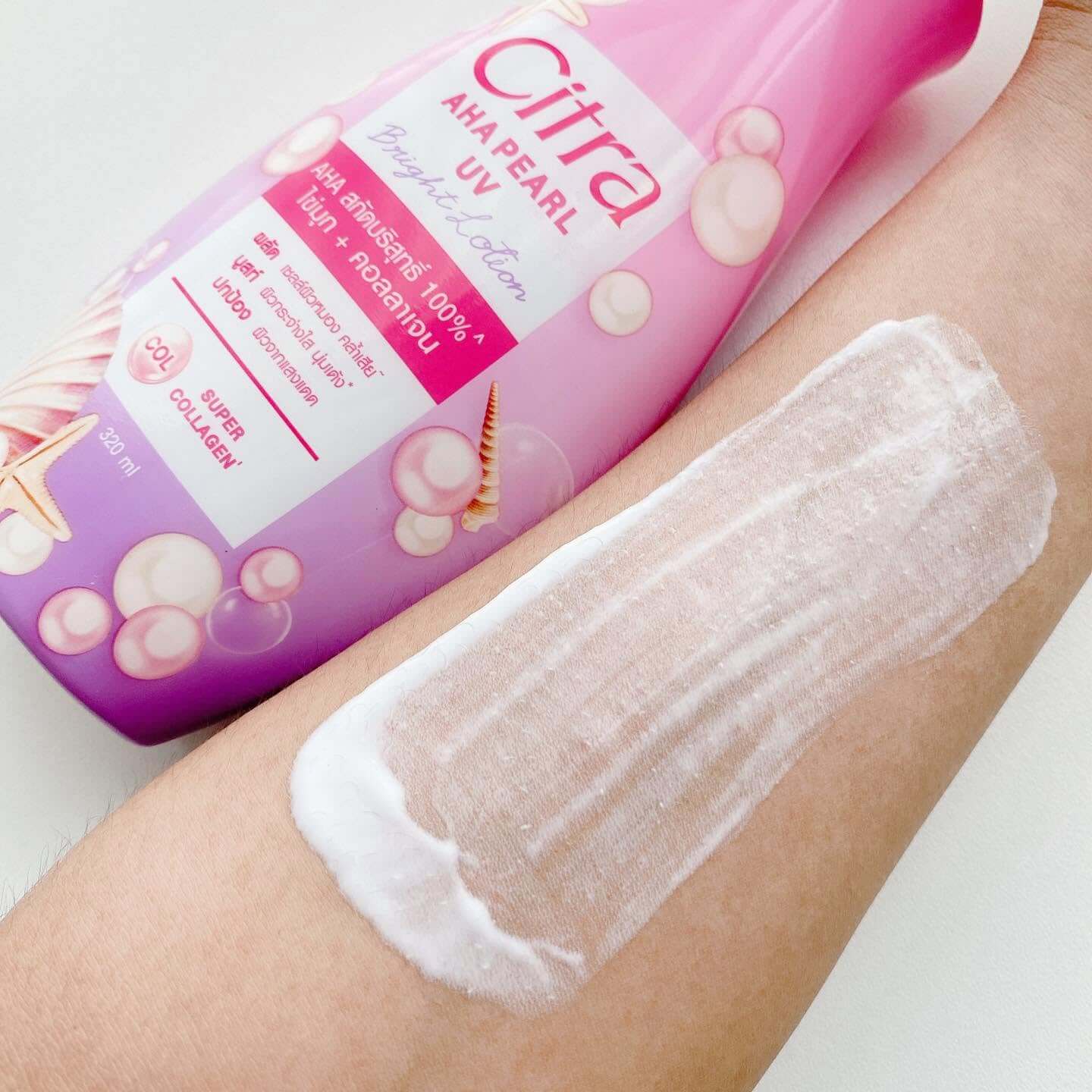 Citra AHA Pearl UV Lotion bottle with lotion spread on skin for smooth body care.