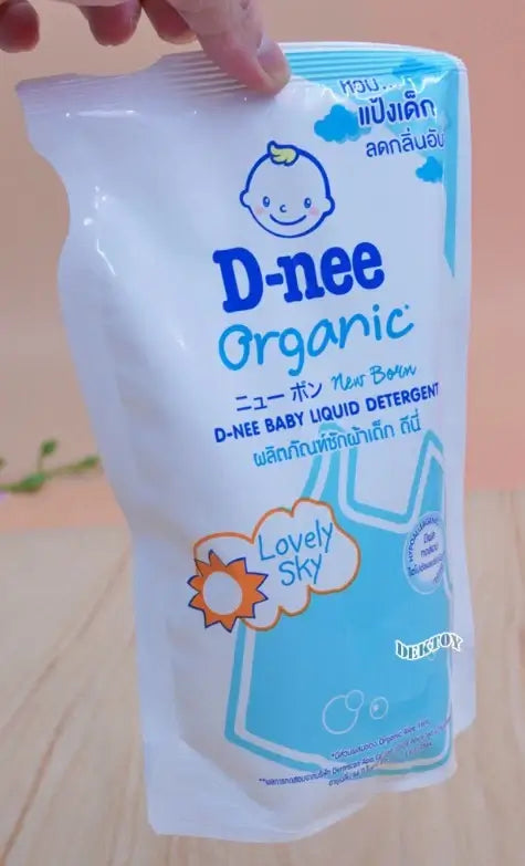 D-nee Baby Detergent New Born Liquid Wash Lovely Sky Refill 530ml packaging on a wooden table.