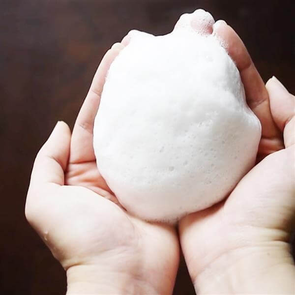 Deitanseki Charcoal Clay Soap lather created in hands, showcasing its foamy texture for facial cleansing.