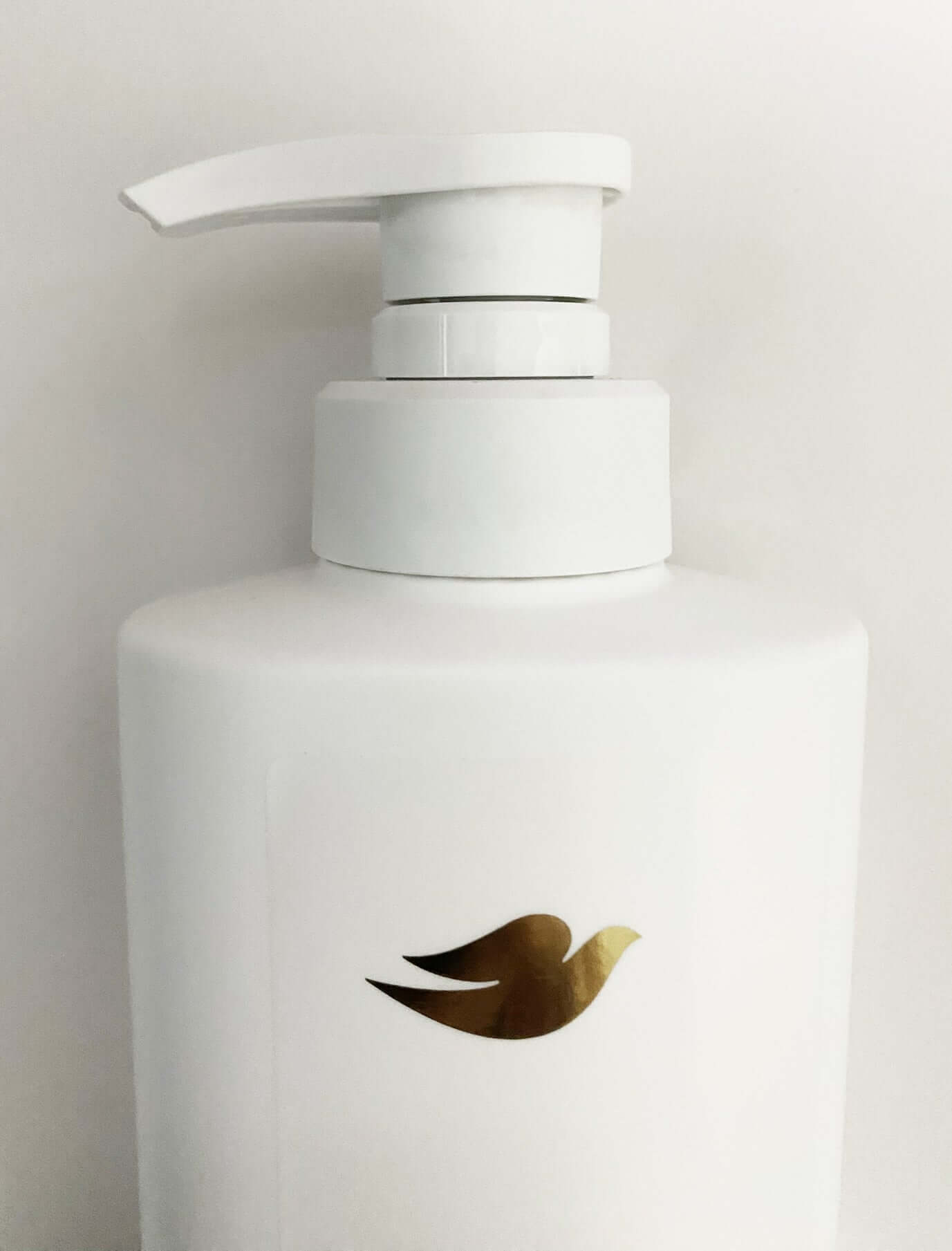 Dove Elastin Shampoo bottle with pump top and gold logo on white container.