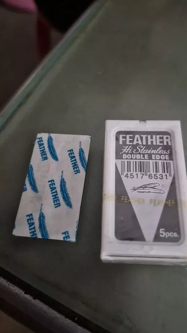 FEATHER Razor Blades Hi Stainless Platinum Double Edge packaging and blades displayed on a surface.