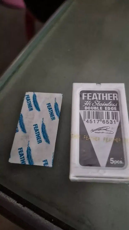 FEATHER Razor Blades Hi Stainless Platinum Double Edge packaging and blades displayed on a surface.