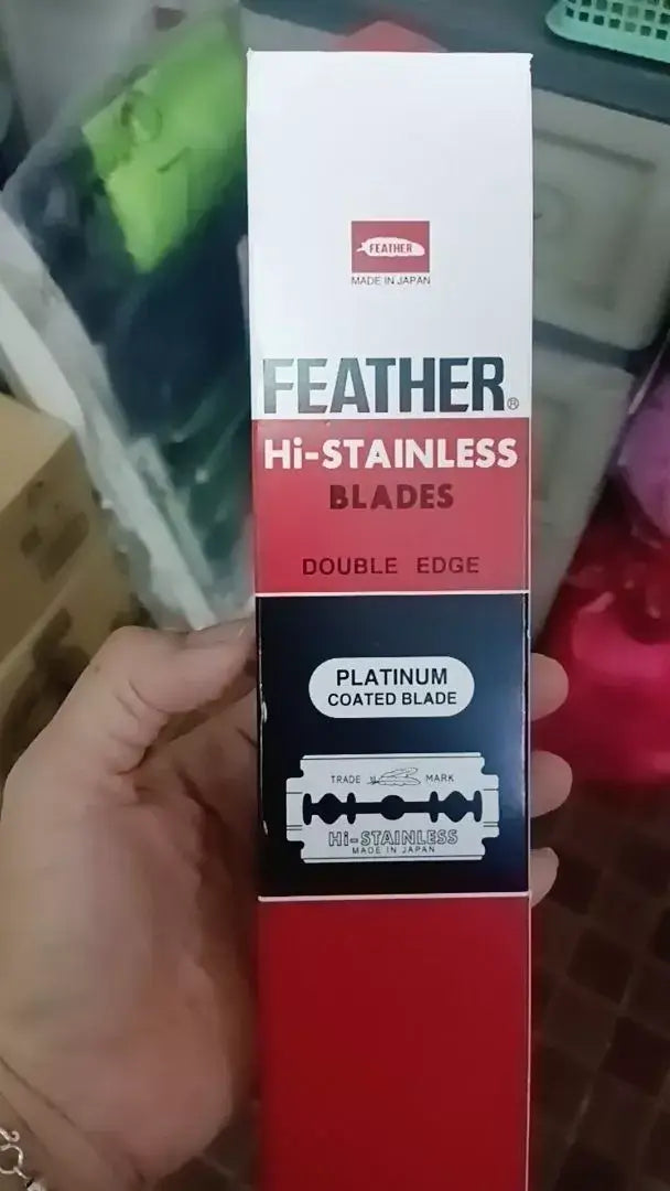 FEATHER Razor Blades Hi Stainless Platinum Double Edge packaging held by a hand, showcasing the product's branding.