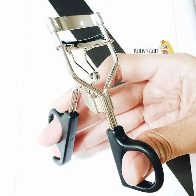 GINO McCRAY Eyelash Curler held in hand, showcasing its sleek design for professional makeup application.