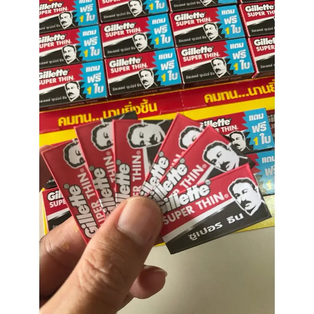 Hand holding multiple packs of Gillette Super Thin double edge razor blades