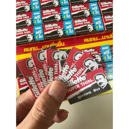 Hand holding multiple packs of Gillette Super Thin double edge razor blades