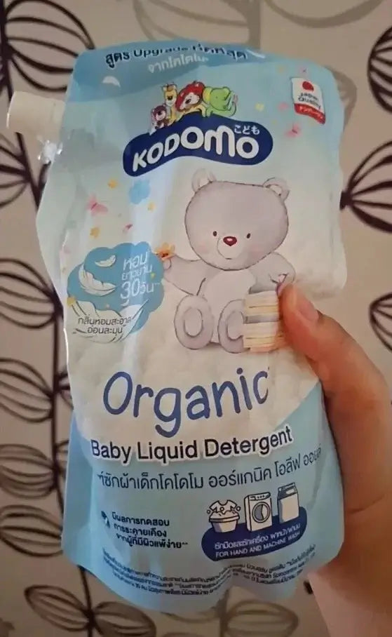 KODOMO Baby Liquid Detergent Organic packaging held in hand, gentle cleaning for baby clothes.