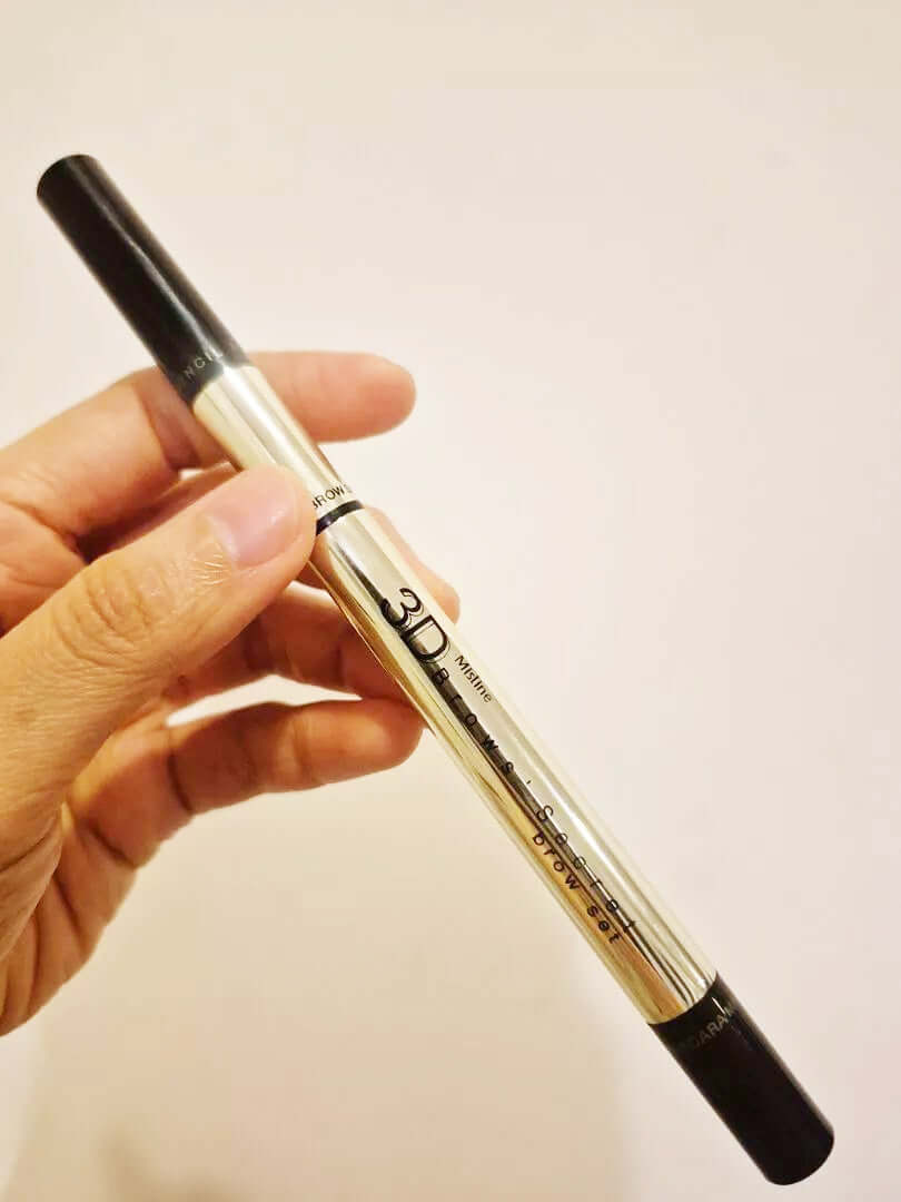 Hand holding Mistine 3D Brows Secret 3 in 1 eyebrow pencil stick