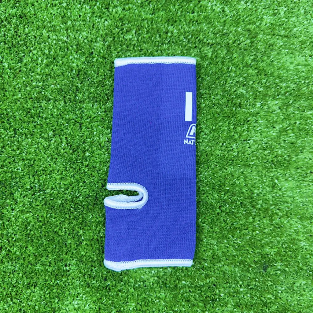 Nationman Ankle Guard on green turf, featuring elastic compression support for sports like Muay Thai and MMA.
