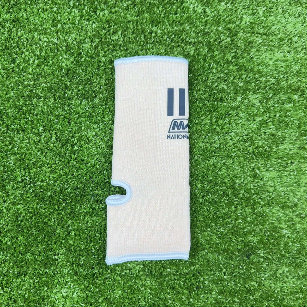 Nationman Ankle Guard, elastic sports compression support for Muay Thai, boxing, and MMA, on green turf.