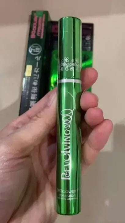 A hand holding the ODBO BQ Cover Mascara green tube in front of its original box.