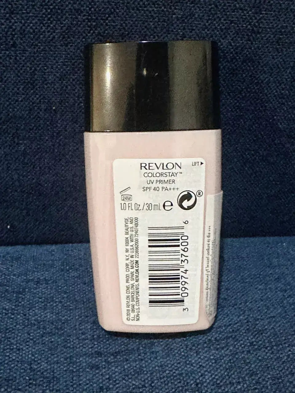 Revlon ColorStay UV Primer bottle back view showing the barcode, ingredients, and product details on a dark blue texture background.
