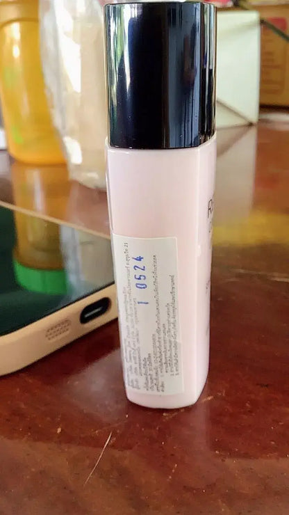 Revlon ColorStay UV Primer bottle standing upright on a wooden surface with a soft-focus background.