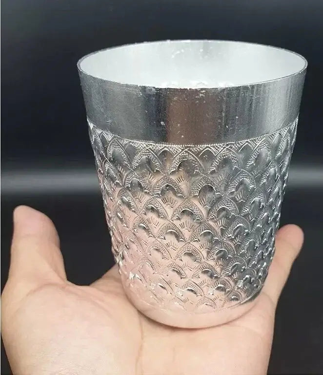 Thai Aluminum Cup featuring traditional embossed design held in hand, perfect for cold beverages.