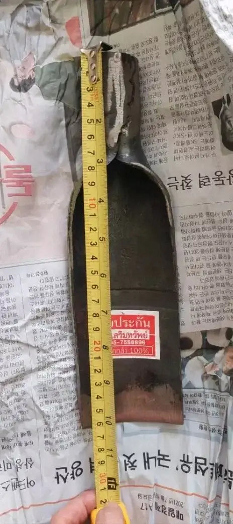Measuring the length of a Thai Spade Head Shovel metal blade using a yellow tape measure tool.