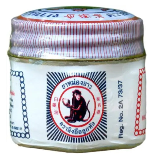 Close-up of White Monkey Balm glass jar label with logo of monkey holding peach