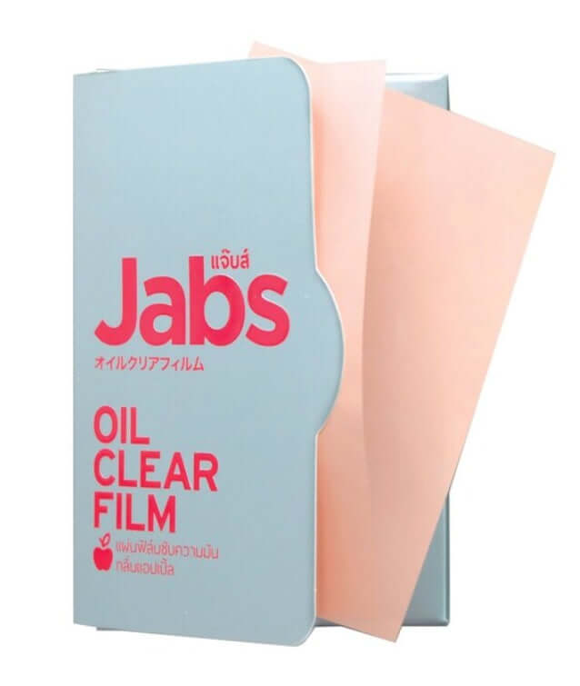 Close-up shot of the Jabs Oil Clear Film product case, with one loose peach-colored sheet, clearly showing the red and English/Japanese text.