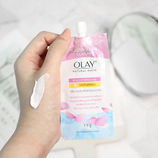Olay Natural White Pinkish Fairness cream sachet in hand, 7.5g, for brightening and UV protection.