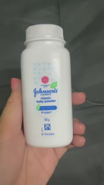  Hand holding Johnson’s Baby Powder Classic Scent 50g showing product label and size
