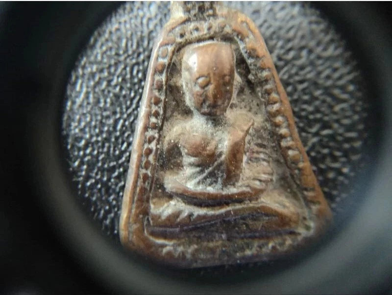 Close-up view of a Buddha amulet inspected with Canon 10x Magnifier, showcasing intricate details and craftsmanship.