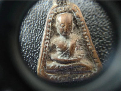Close-up view of a Buddha amulet inspected with Canon 10x Magnifier, showcasing intricate details and craftsmanship.