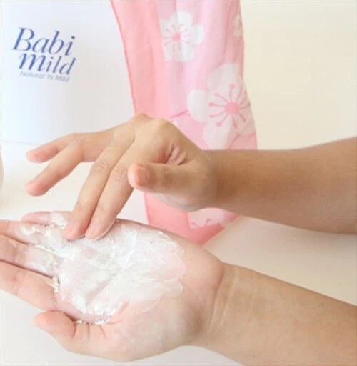 Babi Mild White Sakura Baby Powder being applied to a baby's hand, showcasing the gentle organic formula.