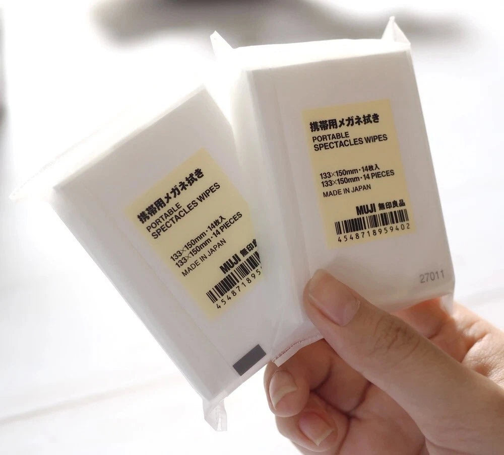 Hand holding MUJI Lens Wipes Japan individually wrapped sachets for travel use