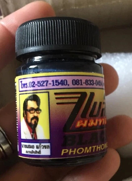 Black Phomthong Hair Growth beard cream jar held in hand close up