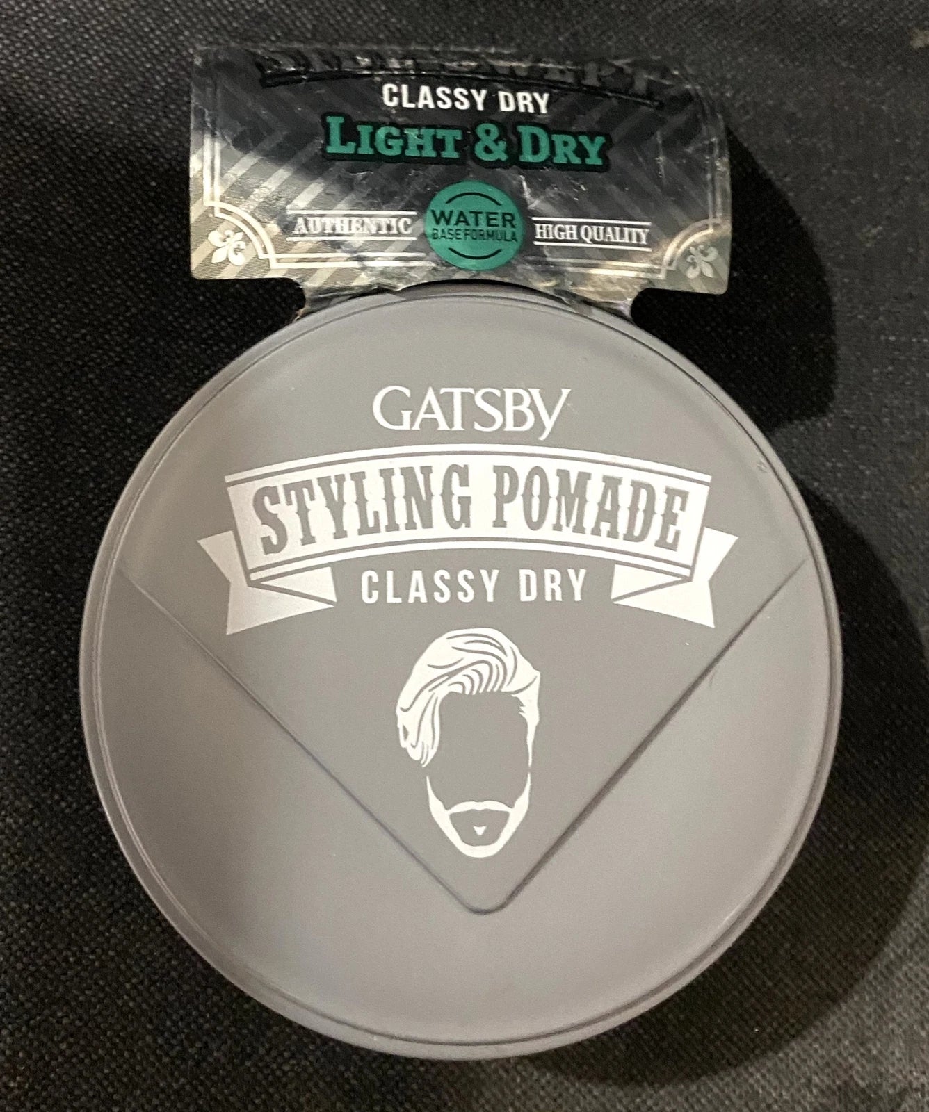 Top view of the GATSBY Classy Dry Pomade jar, showing the gray lid and embossed logo.