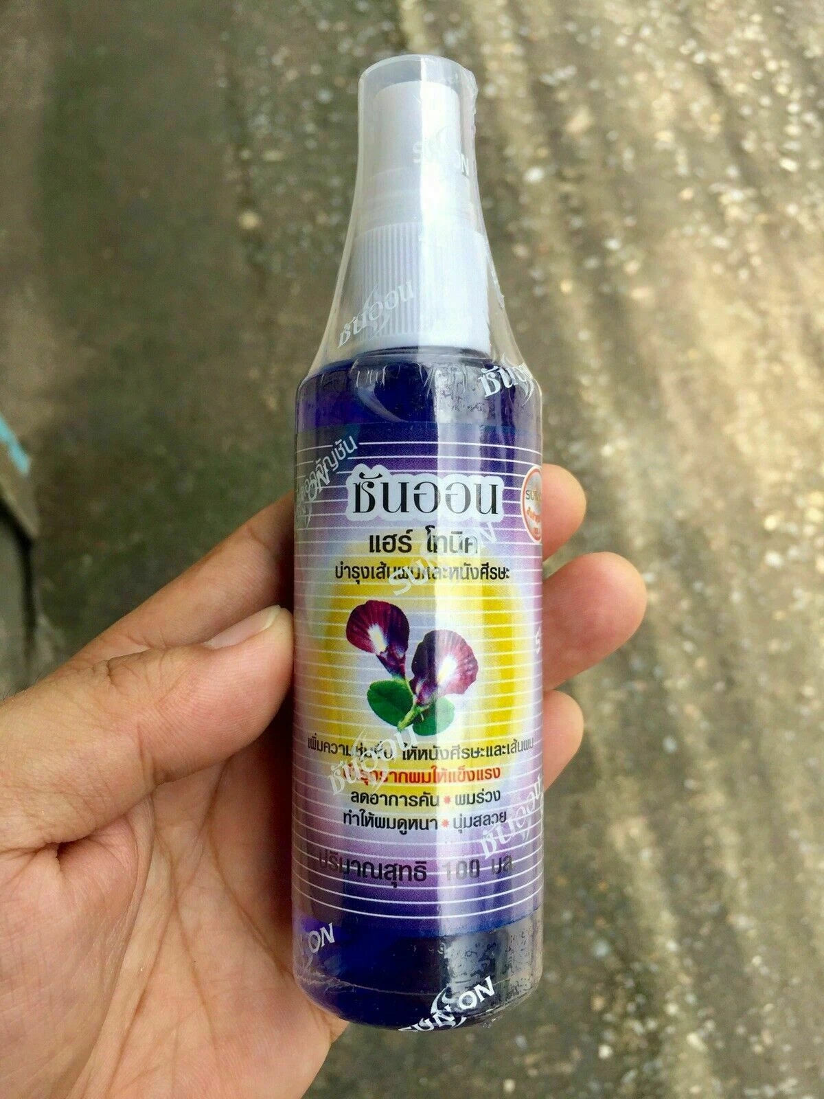 Sun On Hair Tonic Butterfly Pea 100ml held in hand outdoor