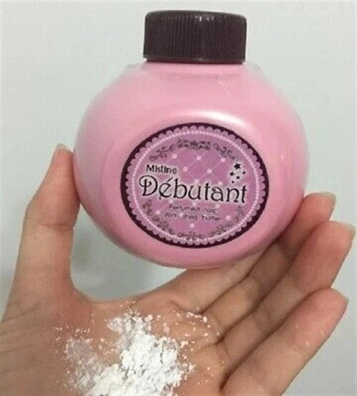 Mistine Debutant Perfumed Talc in pink container held in hand, showcasing fine powder texture and branding.