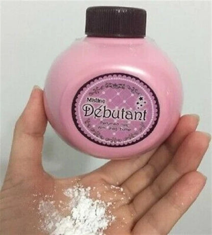 Mistine Debutant Perfumed Talc in pink container held in hand, showcasing fine powder texture and branding.
