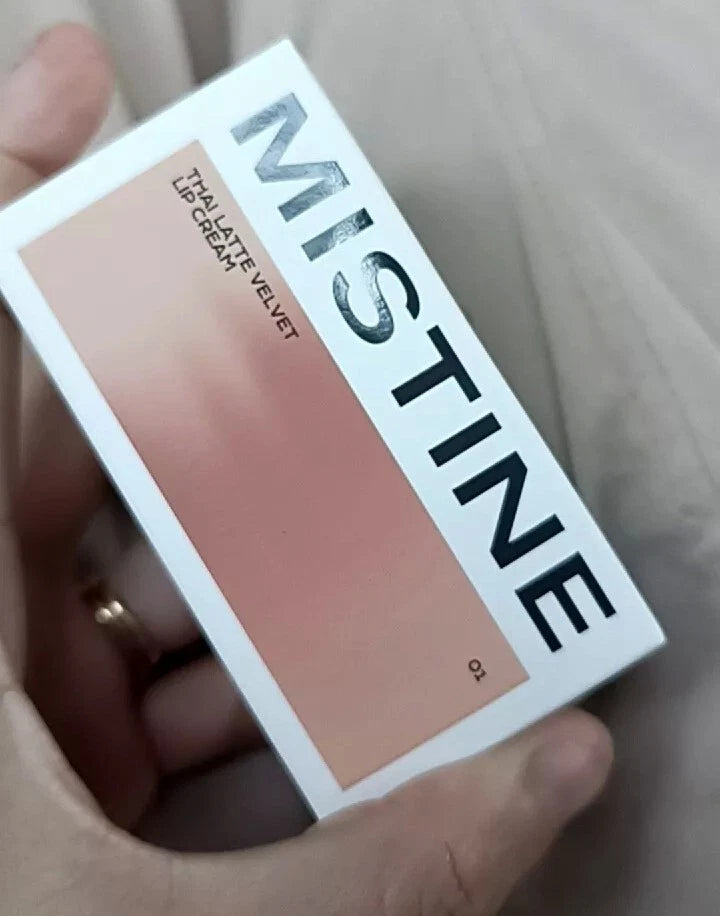 Mistine Velvet Lip Cream white outer packaging held in hand showing brand and color gradient.