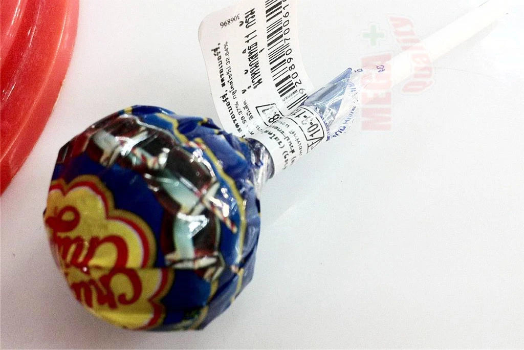 Close up of hand holding a Chupa Chups Cola flavor lollipop