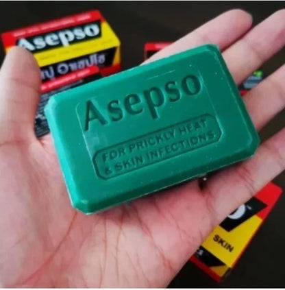 A hand holding an Asepo green soap bar, with the product's box visible in the background.