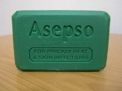 Asepo green soap bar on a wooden surface, showing the embossed text "Asepso FOR PRICKLY HEAT & SKIN INFECTIONS."
