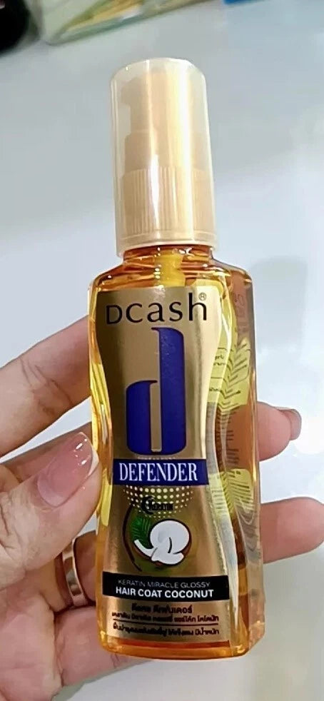 Dcash Defender Hair Coat Coconut Keratin Miracle Glossy Serum 50ml in a hand, showcasing its glossy packaging and application.