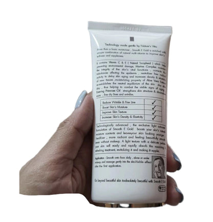 Hand holding Smooth E Gold Cream tube 30g showing the back of the packaging