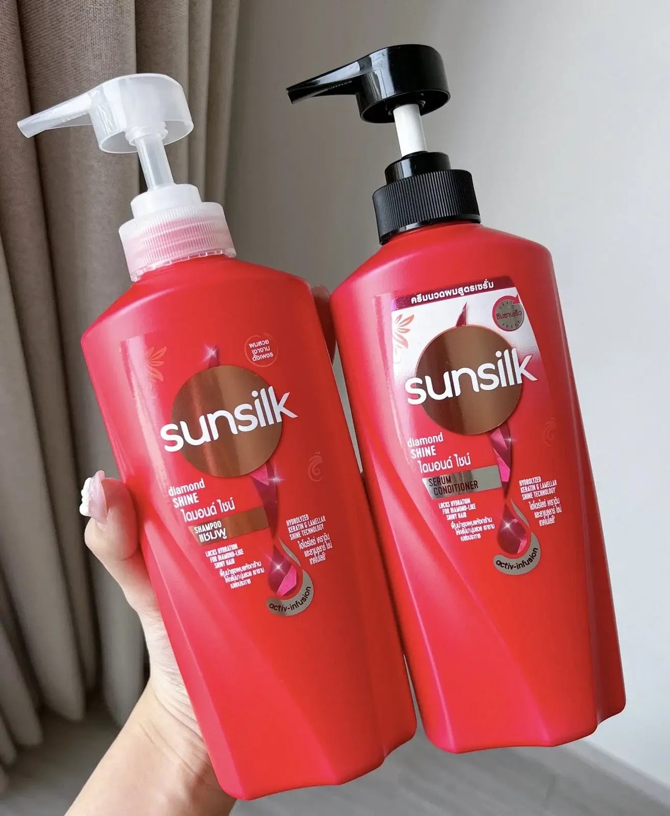 Sunsilk Diamond Shine shampoo and conditioner bottles held in hand showing red packaging design
