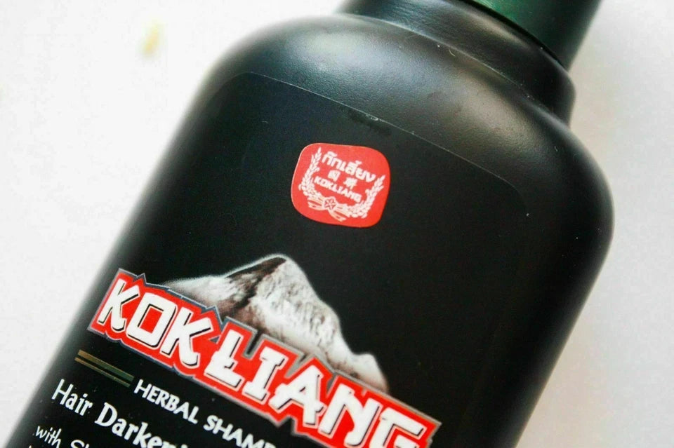 Kok Liang Hair Darkening & Thickening Shampoo bottle close-up with herbal branding on black packaging