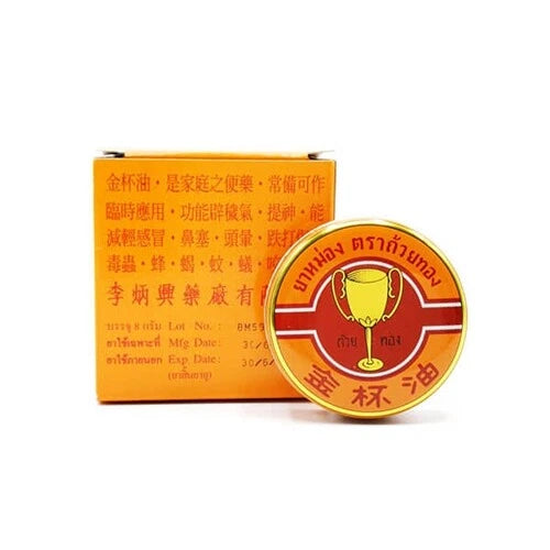 Thai Golden Cup Monkey Holding Peach White Balm herbal ointment jar with packaging for pain relief and healing.